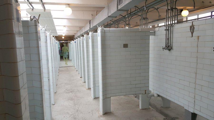 A room full of white tiled shower cubicles