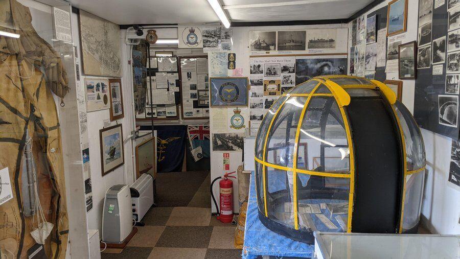 Photos and documents on display and in the foreground , the yellow and perspex gun turret from an A/S rescue launch