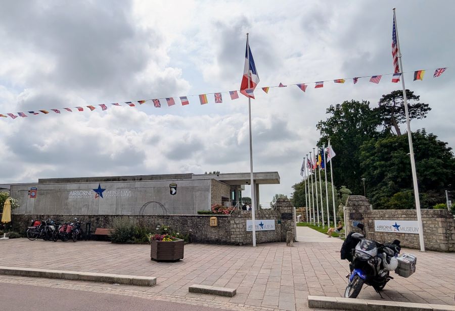 A low light-coloured concrete building with 'Airborne Museum' written on it in large letters