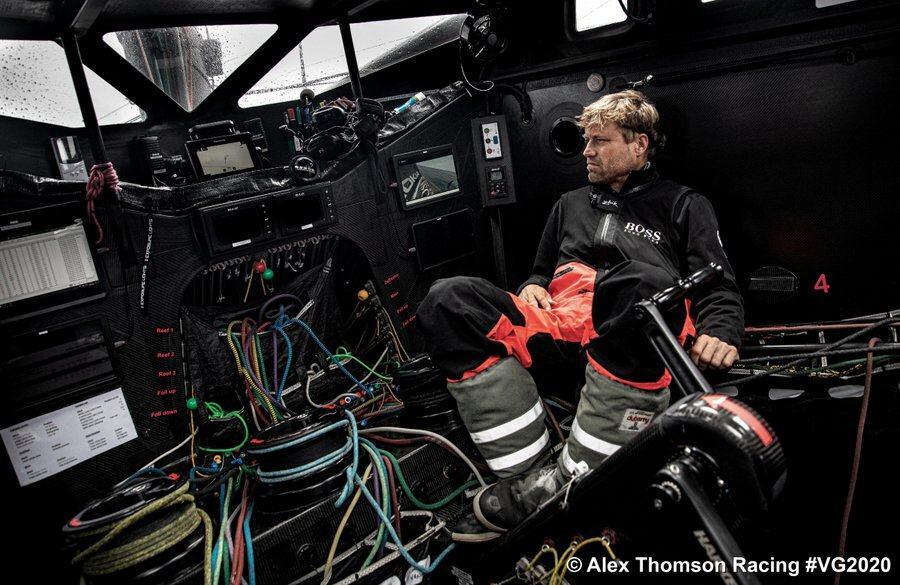 Skipper Alex Thomson in black oilskins among the ropes and screens in his cabin