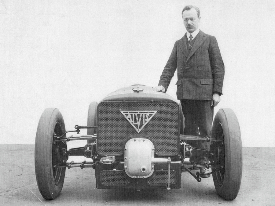 Black & white photo of the car with its designer standing beside it.