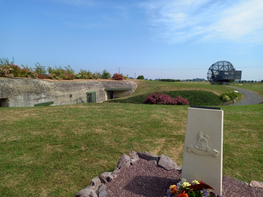 A monument to the RAPC in the foreground with a large buried bunker behind and the radar dish in the background