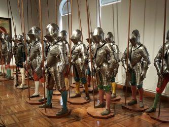 19 mannequins standing together wearing shiny foot soldiers armour and coloured leggings, holding pikes