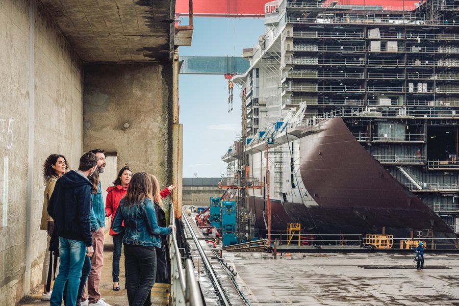Visitors look at a ship under construction