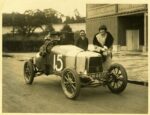 Black & white photo of three people posing in and behind the Aston Martin A1 sports car with a large white number 15 painted on it.