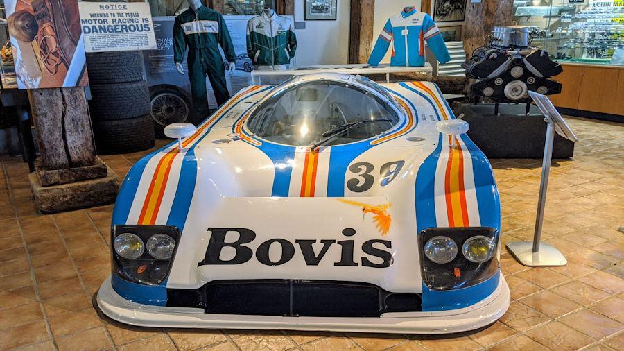 A white motorsports racing car with blue and orange striped markings - The Aston Martin Nimrod