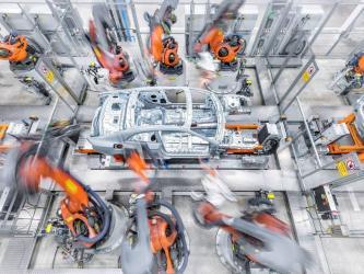 Fast moving orange robot arms work on a car chassis in the Audi factory