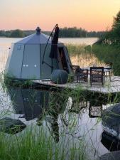 A floating igloo with a deck on a lake at sunset