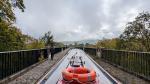 View from the back of a narrowboat along a stone aquaduct above the trees below. A man is walking ahead on the footpath