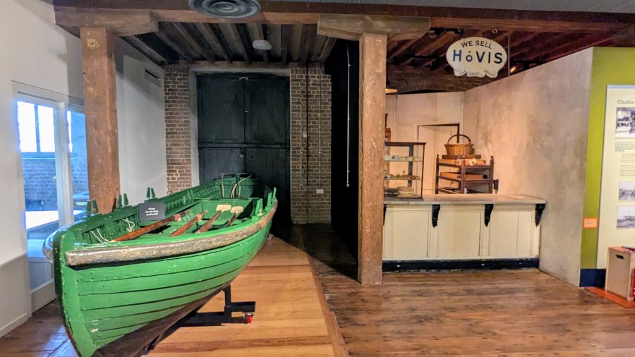 A green rowing skiff sits alongside the shop counter of a replica 1930s bakery