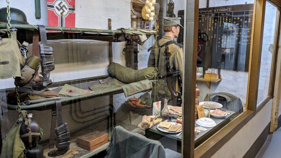 A diorama of a barracks area with bunk beds a German soldier and food on the table