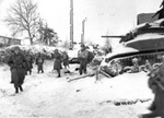 Troops and vehicles move about the street in deep snow