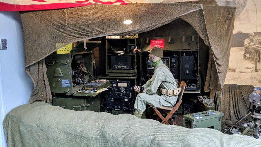 a diorama of a radio tent on the beach with a soldier sat on a chair