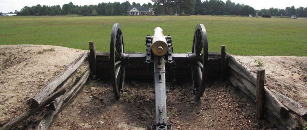 Cannon in an earthwork entrenchment at Bentonville, looking across a green field