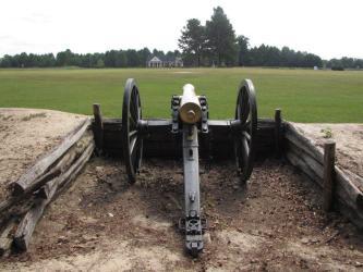 Cannon in an earthwork entrenchment at Bentonville, looking across a green field