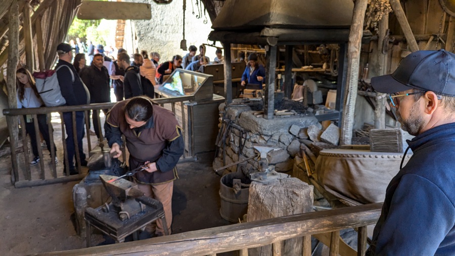 Visitors watch a blacksmith at work in his 9th century hut