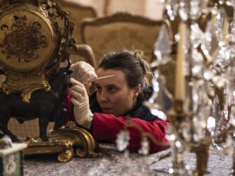 A woman conservator works delicately on an antique clock