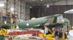 Two men work on a green painted Bristol Beaufighter in a hanger