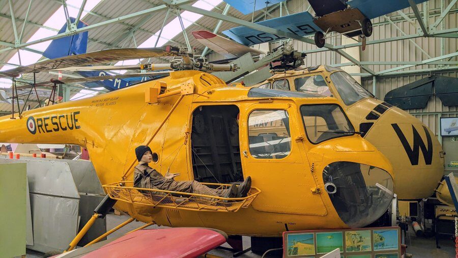 Bright yellow helicopter with a mannequin lying in a rescue stretcher hanging outside