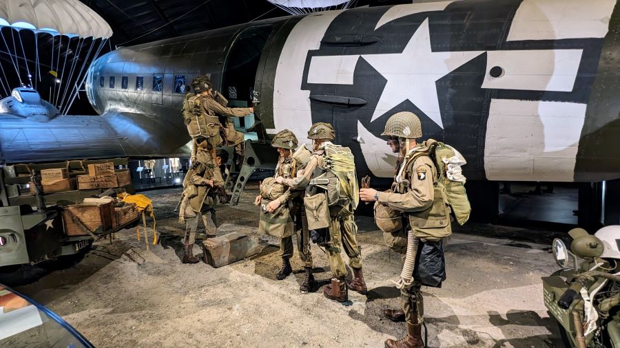 Paratroopers (mannequins) in their full gear, line up to board their aircraft