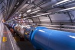 A large blue tube surrounded by equipment, runs through a tunnel at CERN