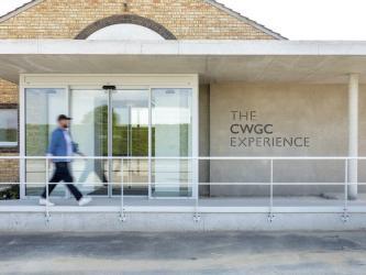 A man walks towards the glass door entrance of the Commonwealth War Graves Commission Experience