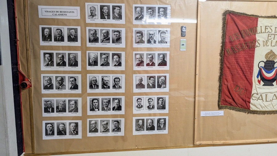 Black & white mugshots of 51 men displayed on a wall next to a flag