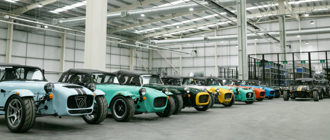 A row of multi-coloured sports cars in a large new hanger-like building