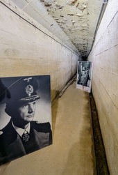 A long, narrow, whitewashed passageway with two large B/W photos propped up in it.