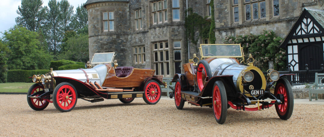 Two Chitty Chitty Bang Bang classic cars sit on the gravel drive outside Palace House at Beaulieu