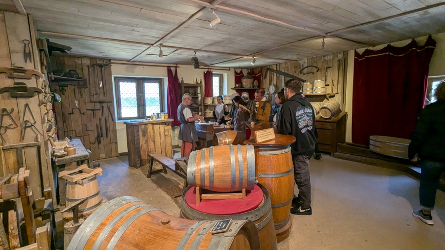 Visitors listen to the cooper in his shop