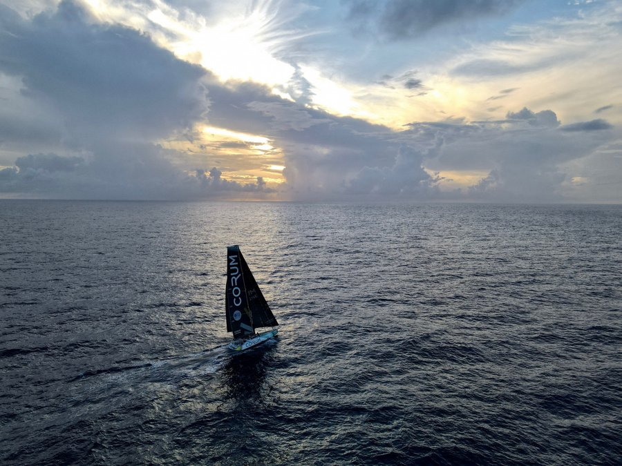 A solitary Transat Jacques Vabre racing yacht at dusk on the calm waters of the Atlantic