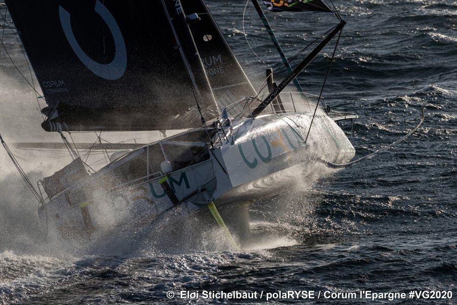 Bow on view of Vendee Globe competitor, Corum L’épargne lifts out of a wave with spray
