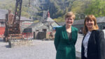 Two women stand in front of historic buildings in a slate quarry