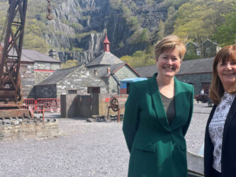Two women stand in front of historic buildings in a slate quarry