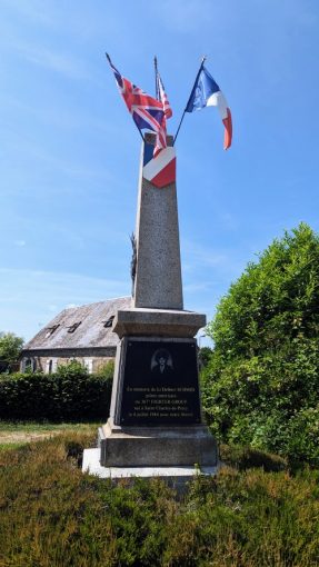 A memorial obelisk with flags on top, in a church yard