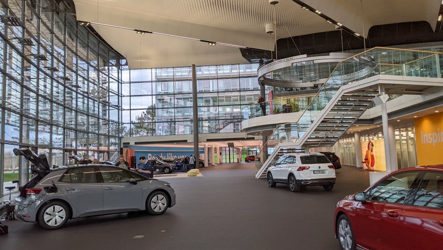 A large indoor space with people gathered around cars