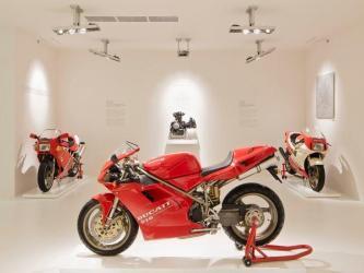 Red race bikes on display in a white room at the Ducati Museum