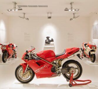 Red race bikes on display in a white room at the Ducati Museum