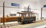 A large scale model of an early Austrian tram displayed on a track with the electric catenary above