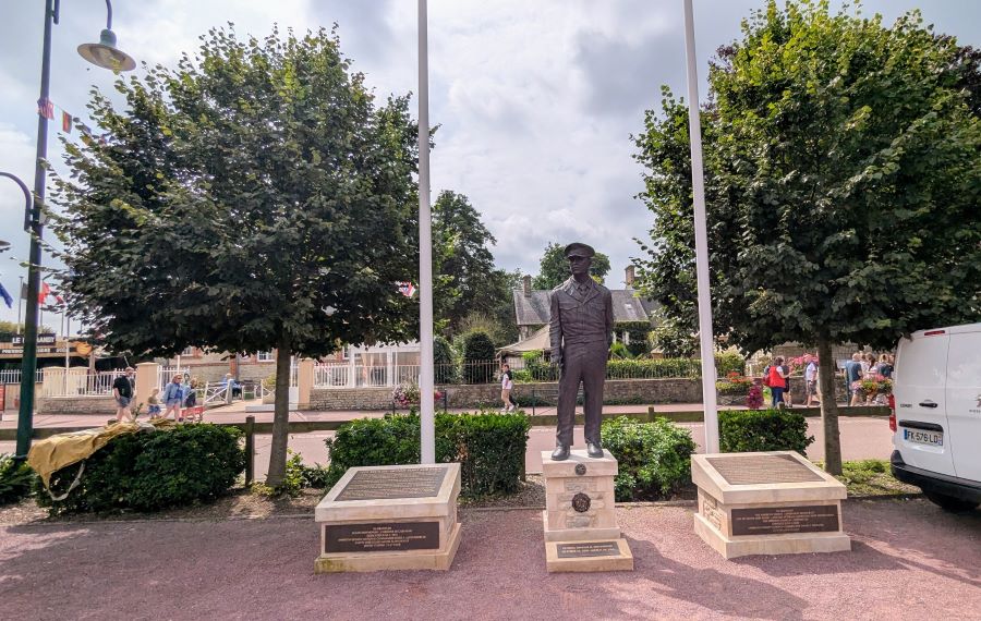 Lifesize statue on a plinth with memorial plaques on either side