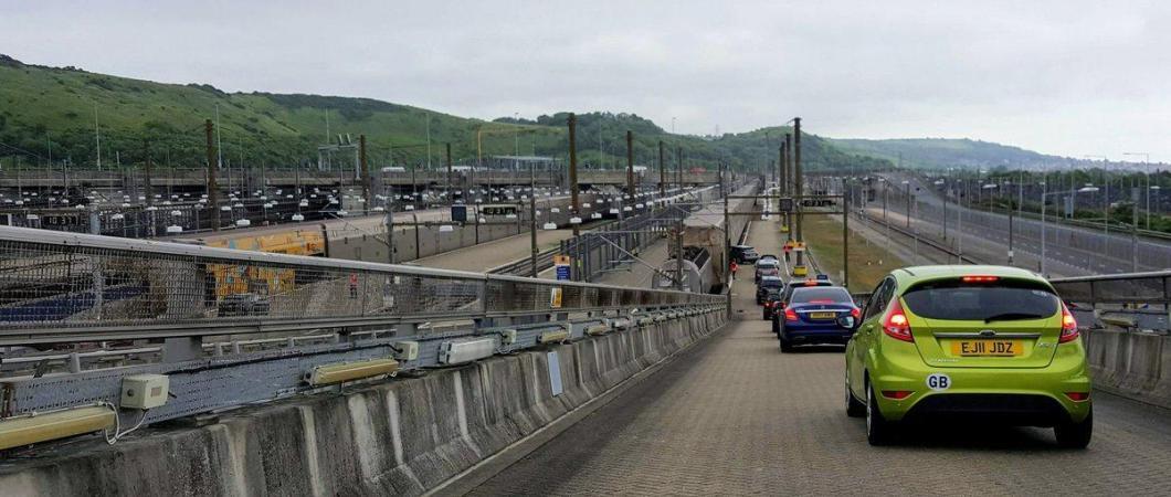 A line of cars driving down the ramp to a Eurotunnel Shuttle train