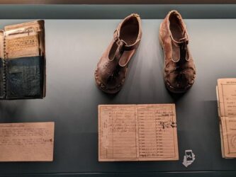 Display case of official documents needed by Parisians under occupation, and a pair of child's shoes