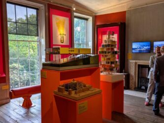 A room with orange info panels on the wall and architectural models displayed in the centre