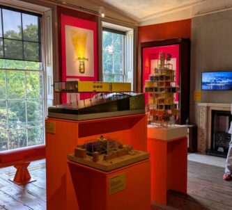 A room with orange info panels on the wall and architectural models displayed in the centre