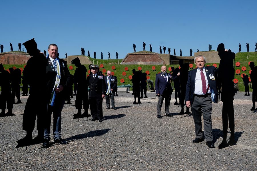 Middle aged Falklands veterans stand among the Falkland Tribute silhouettes in the gravel courtyard of Nothe Fort on a sunny day