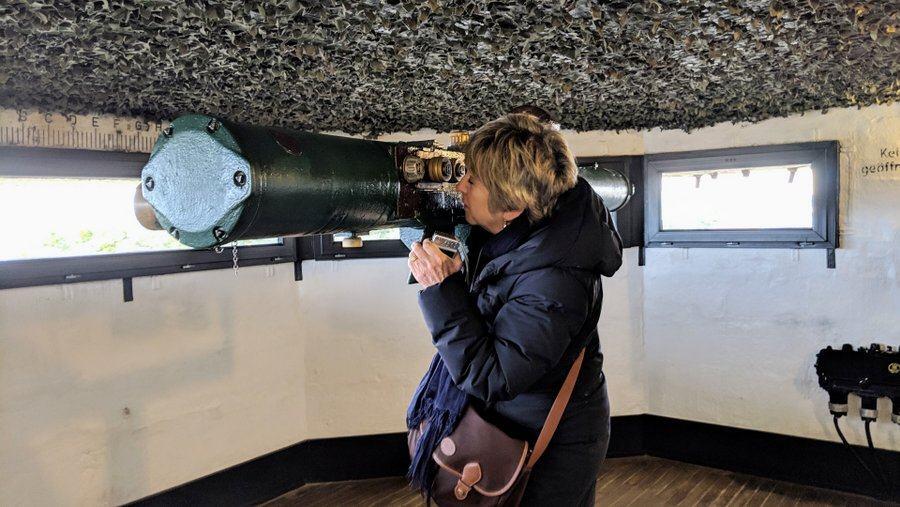 A woman looks through the eyepiece of a large rangefinder