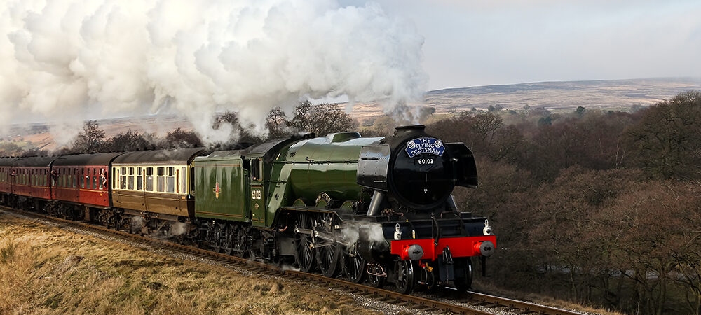 Flying Scotsman steaming through the countryside with period coaches behind her