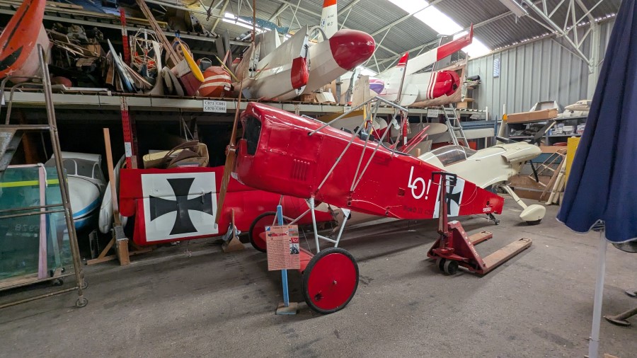 The wings and fuselage of a red-painted German WW1 fighter awaiting restoration