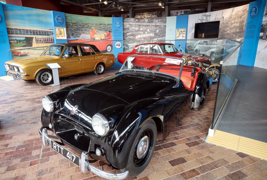 A number of cars from the 1950/60s on display with a black sportscar in the foreground